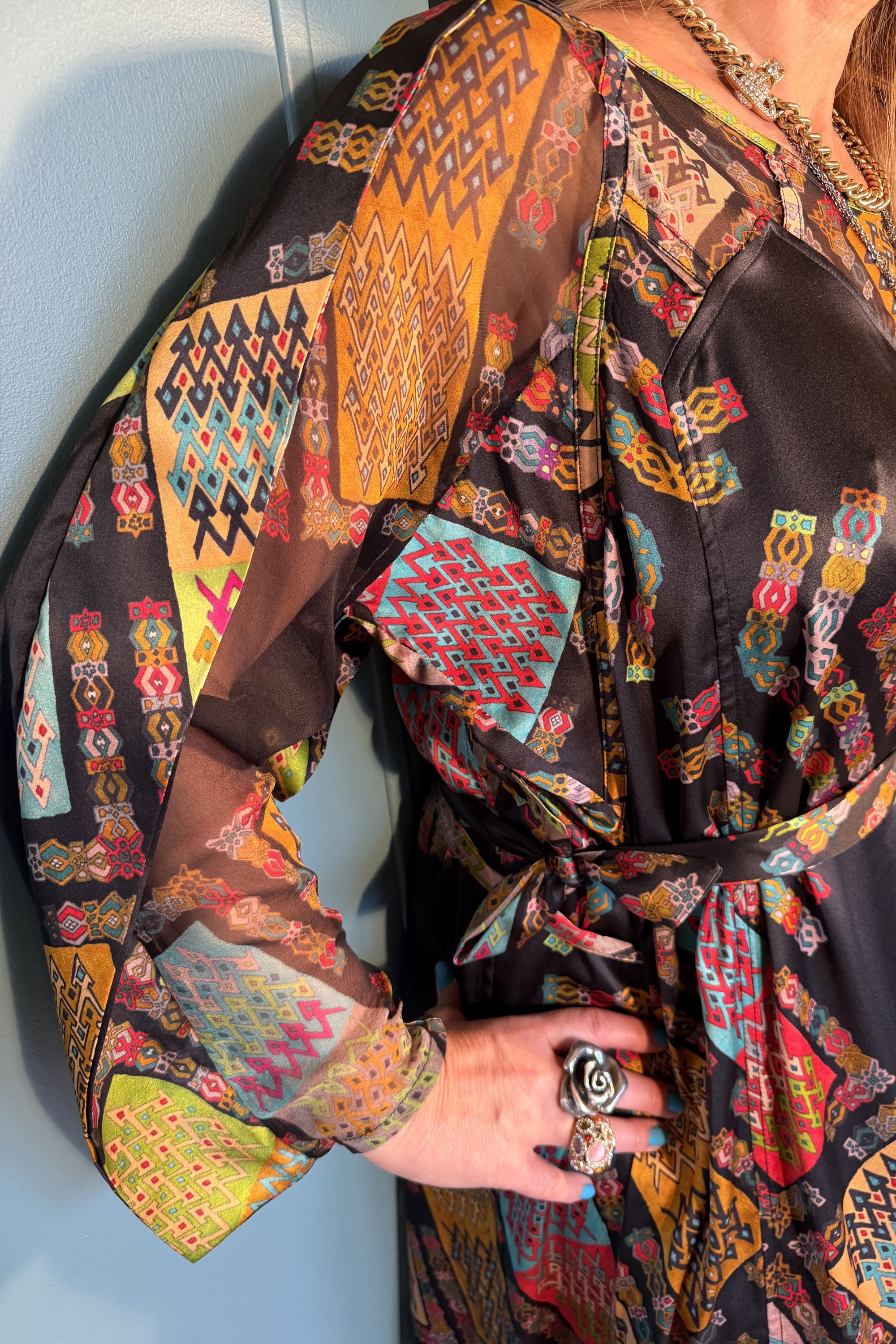 Close-up of the Josephine Harly Black silk dress showing sheer chiffon sleeves, colourful geometric print and waist belt
