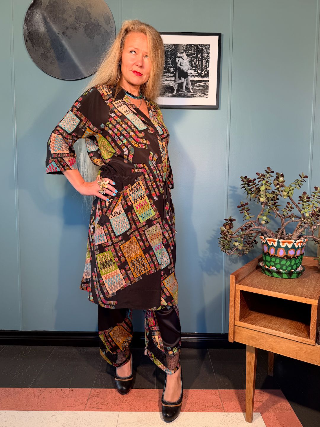 Full-length view of Rimini Black Harly silk dress styled with matching trousers in the original Kron by Kronkron print
