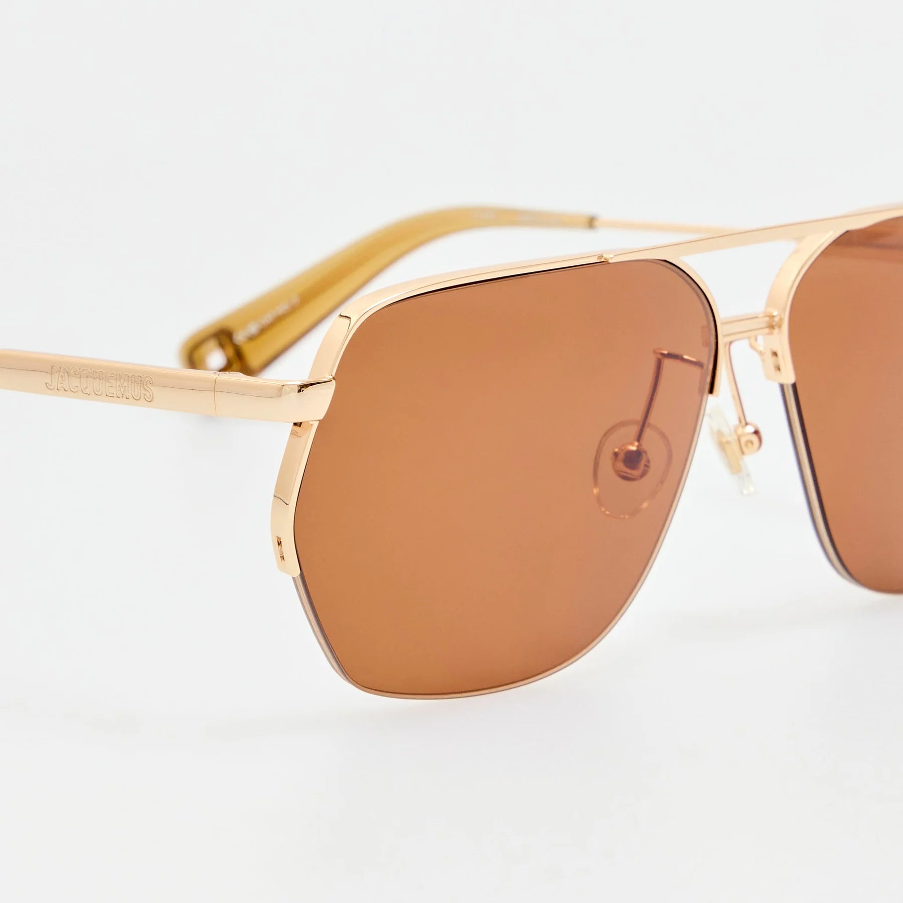 Close-up of Jacquemus Aviador sunglasses in light gold with brown lenses and logo detail