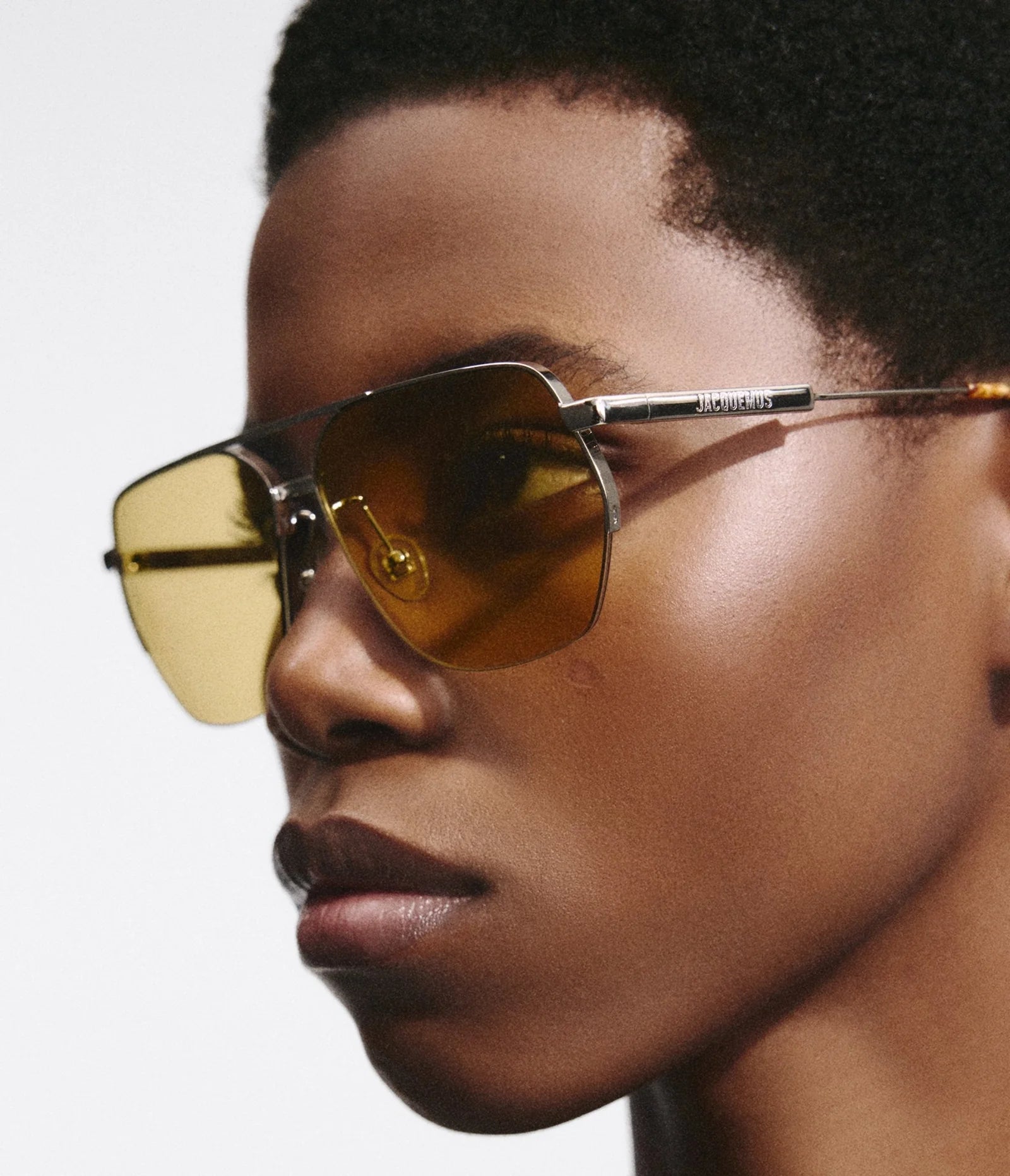 Model wearing Jacquemus Aviador silver sunglasses with yellow lenses, side view