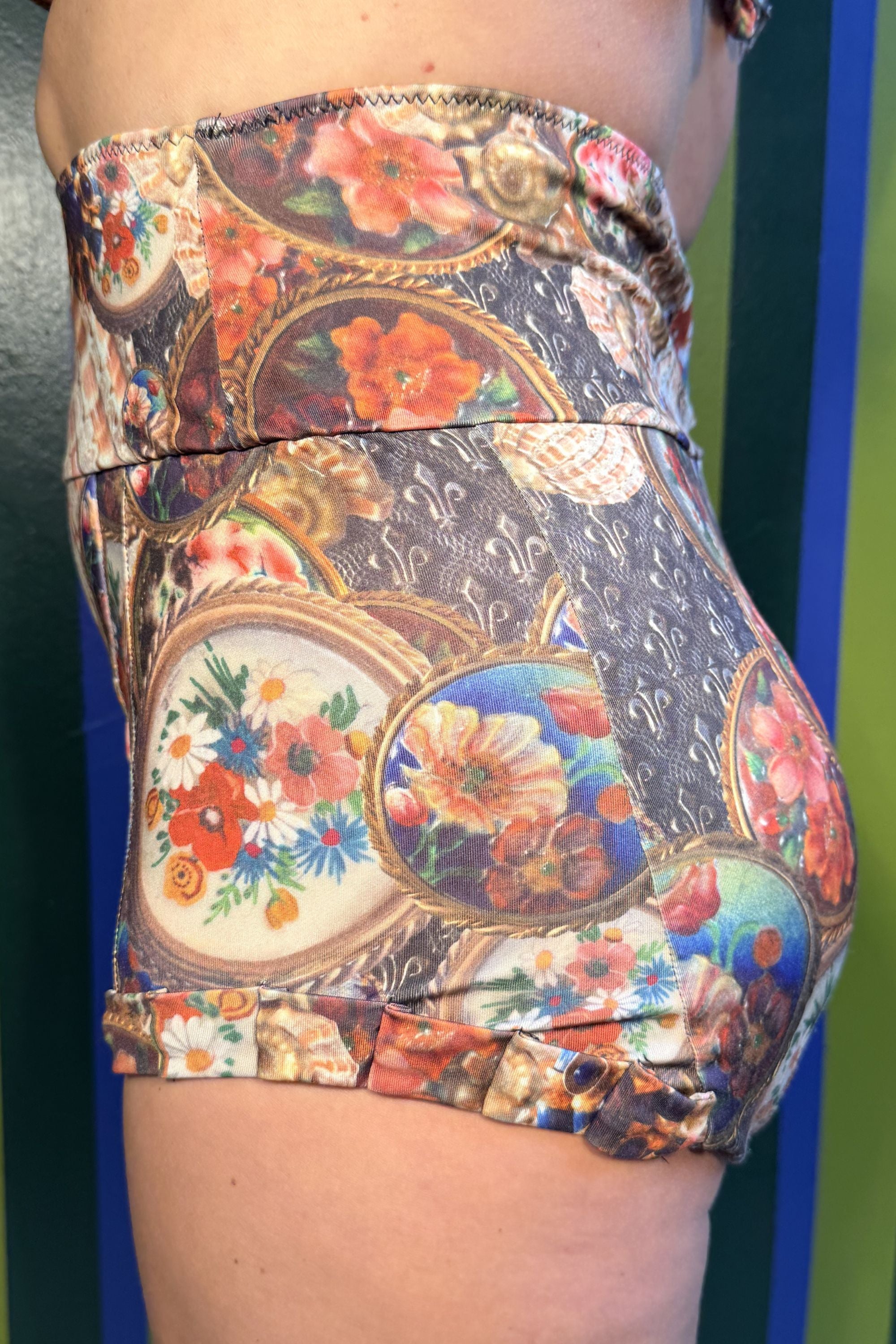 Close-up side view of the Dita Highrise Bikini Bottom in Treasurehunt print by Kron by Kronkron, showing the fold-over waistband and floral artwork.