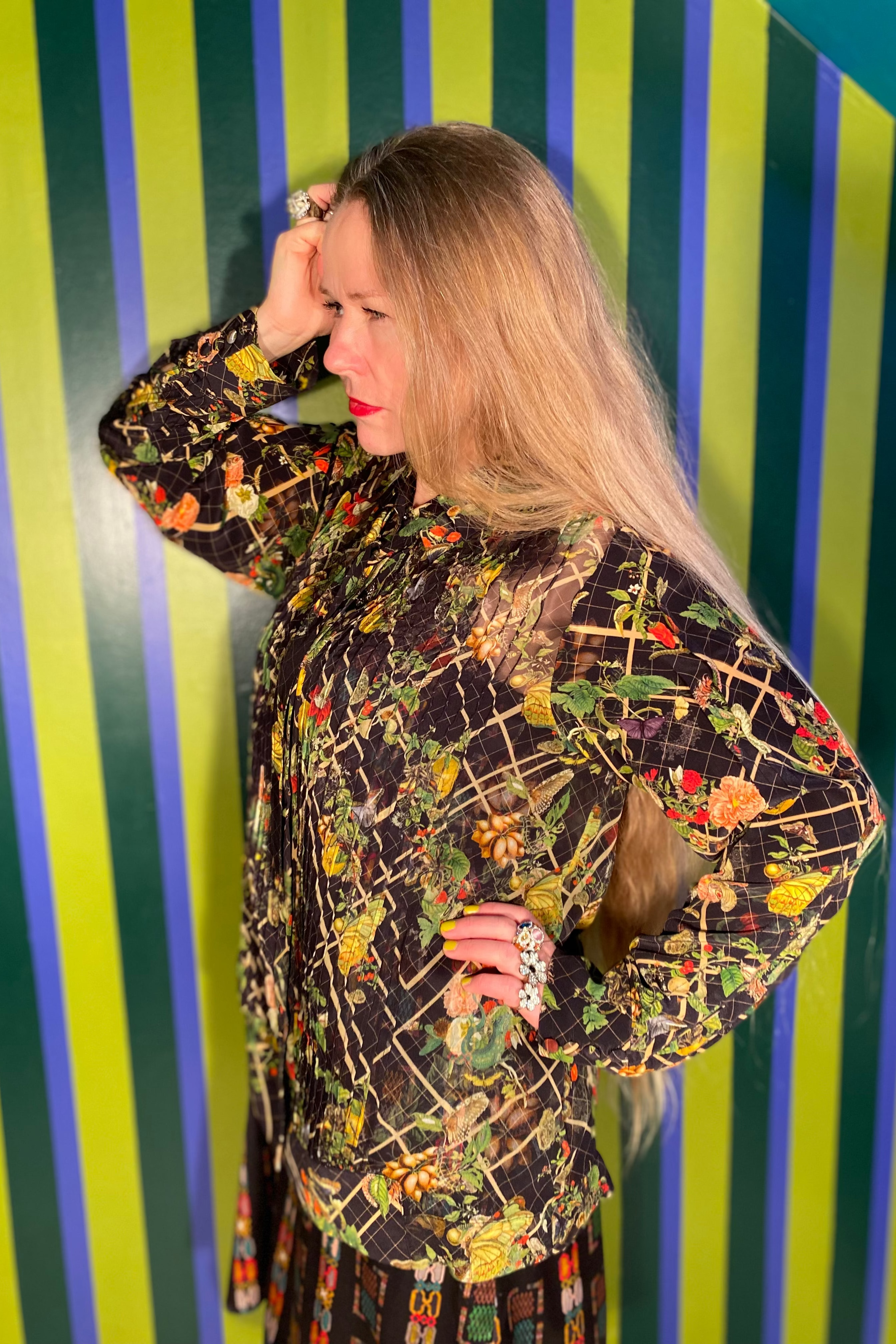 Woman wearing a patterned dress against a striped wall.