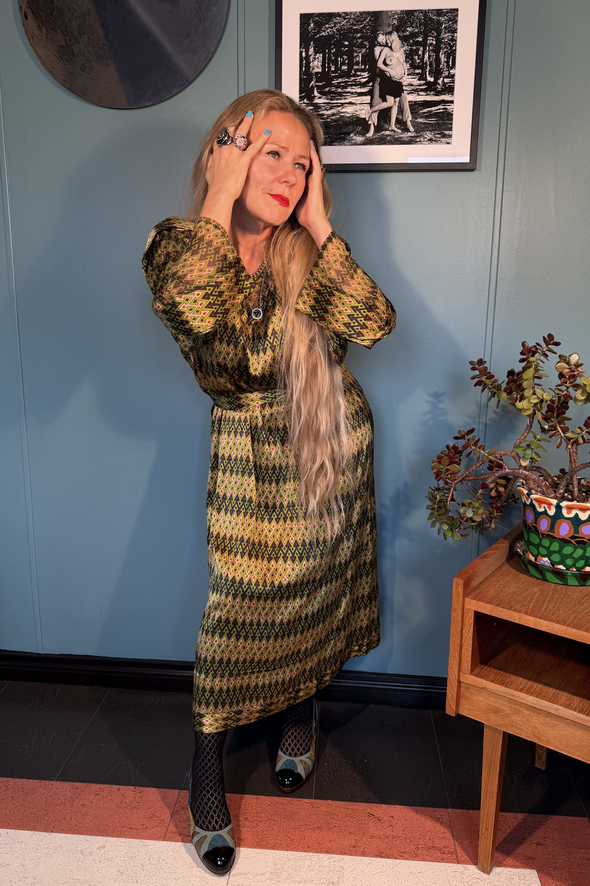 Woman styling the Josephine midi dress in Sporrof Green with long sleeves and adjustable belt